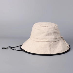 Detail of off-white cotton linen sun hat featuring black trim and adjustable wind cord