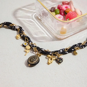 Détail du collier vintage avec cœur émaillé noir, fleurs et ruban de soie entrelacé