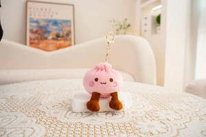 Macro shot of cute pink plush bun charm with embroidered face and golden keychain