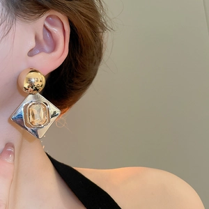 Gros plan sur des boucles d'oreilles géométriques avec pierre champagne et éclat d'or