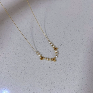 Elegant gold titanium steel necklace featuring natural pearls and small golden bead charms
