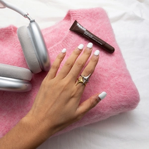 Detail of interlocking star-shaped two-tone gold and silver ring on pink sweater