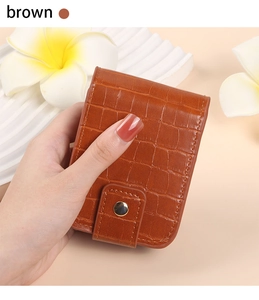Detail of brown faux leather lipstick case with crocodile pattern and metal snap button