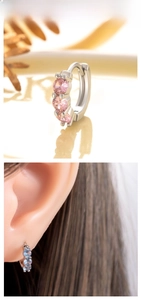 Detail of huggie earrings with pink and light blue zircons on a silver-tone band