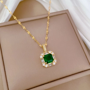 Macro detail of gold necklace with square green emerald pendant and white zircons