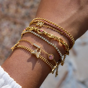 Gold layered bracelet set with pink zircon stones and butterfly charms on wrist