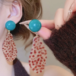 Close-up of leopard print acetic acid teardrop earrings worn on model for detail
