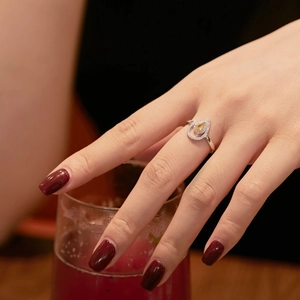 Primer plano de un anillo con gema amarilla en forma de pera y detalles de diamante