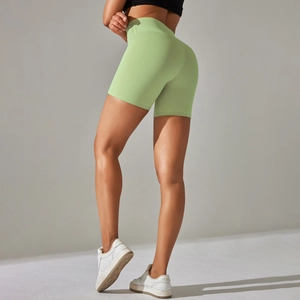 Close-up of light green high-waisted yoga shorts with peach hip shaping and seamless fabric