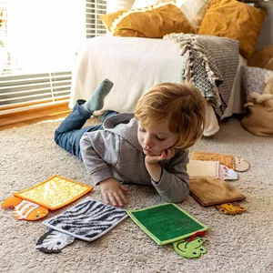 Toddler using animal-shaped sensory tactile mats with various plush fabric textures
