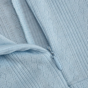 Close-up of light blue knit dress with hollow floral texture and invisible zipper detail