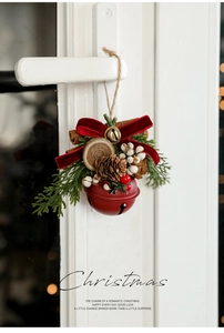 Close-up of Christmas bell ornament with pine cones and red velvet bow on a door