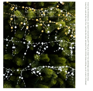 Detail of white and gold crystal bead garland strands on green Christmas tree branches