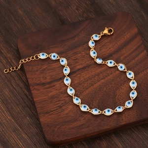 Bracelet œil porte-bonheur doré avec perles bleues sur un fond en bois sombre