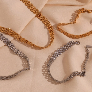 Close-up of woven chain necklace in gold and silver finish on silk fabric