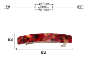 Dettaglio del fermaglio in acetato da 8cm con motivo tartarugato rosso su sfondo bianco