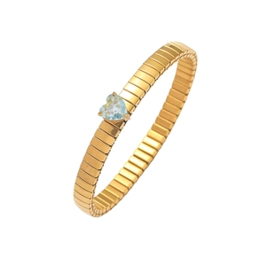 Detail of 18K gold tubogas elastic bracelet featuring a heart-cut blue gemstone