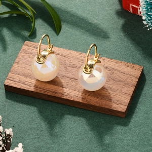 French vintage pearl earrings displayed on a wooden stand with festive green decor
