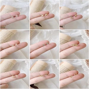 Detailed close-up of small gold stud earrings with star, moon, and heart shapes