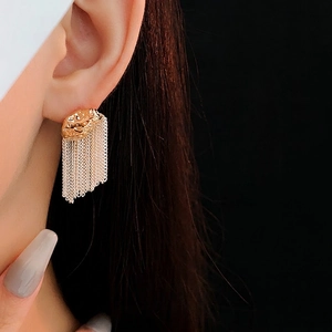 Boucles d'oreilles luxueuses à pompons dorés et disque texturé portées par un modèle