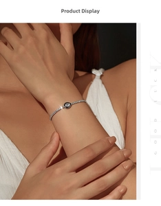 Detail of silver S925 tennis bracelet featuring black enamel water drop on female wrist
