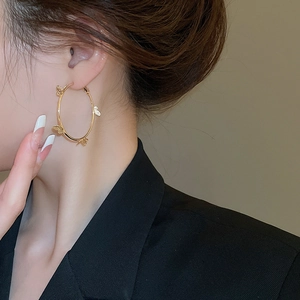 Close-up of golden butterfly hoop earrings worn by a model in a black blazer