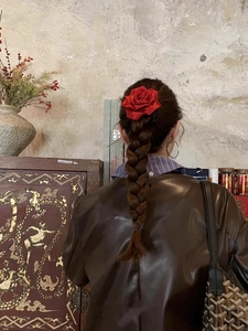 Détail d'une pince à cheveux rose en satin rouge sur une coiffure tressée vintage