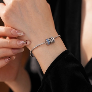 Macro shot of silver bracelet with blue crystal cylinder charm and cubic zirconia inlay