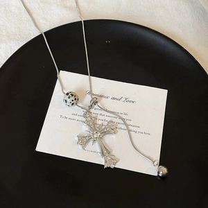 Detailed view of silver snake chain necklace with tiger eye cross and sparkling zircons
