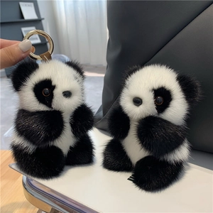 Panda faux mink fur keychain with golden clasp and brown leather strap on soft white surface