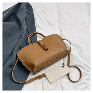 Detail of caramel lychee grain leather tote bag with metallic feet and side structure