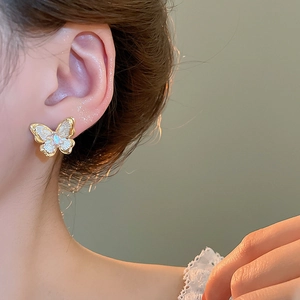Close-up of 18k gold plated butterfly stud earring with shimmering pearl-white wings