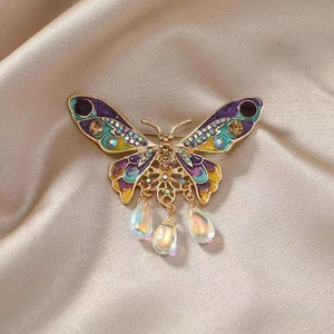 Macro detail of vintage butterfly brooch with colorful enamel and dangling crystal pendants