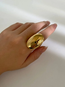 Close-up of a chunky oval gold ring with a polished mirror finish on a hand