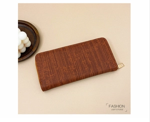 Detail of vintage brown long purse with wood-grain texture and gold zipper closure
