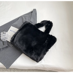 Detail of soft black faux fur tote bag showing plush texture on white bedding