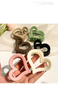 Detail of matte heart-shaped hair claw clips in various colors on white silk background