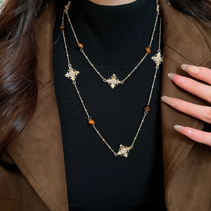 Detail of double-layer gold chain necklace with tiger eye stone and cross pendant