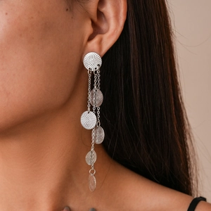 Close-up of silver long tassel earrings with textured round discs on a model