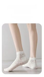 Detail of ballet style white mesh ankle socks with floral patterns and bow accents