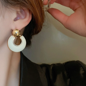 Close-up of elegant gold and cream geometric hoop earrings worn for daily styling
