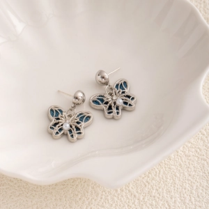 Detailed close-up of butterfly earrings with blue denim fabric, pearls and crystals