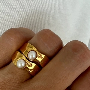 Close-up of 18K gold-plated irregular lava rings with embedded white pearls on fingers