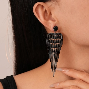 Gros plan de longues boucles d'oreilles à pompons noirs avec franges géométriques