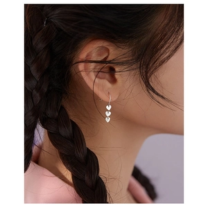 Elegant silver triple heart drop earrings worn by a model in a high-quality side profile
