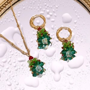 Detail of Christmas tree jewelry set with red and green crystals on mirrored water drops