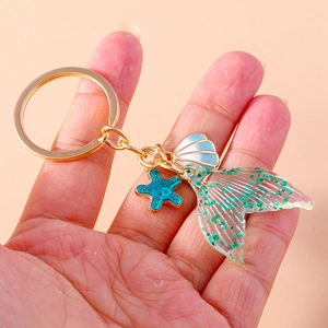 Mermaid tail keychain with blue starfish and shell pendant on golden metal ring