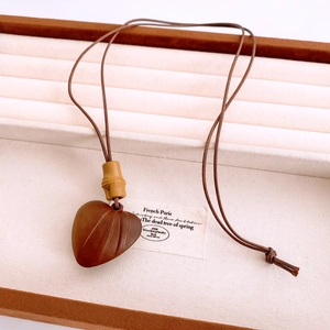 Gros plan du pendentif cœur en bois avec texture de nervures et détail de bambou
