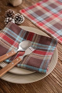 Detail of red and blue checkered Christmas placemat with wooden cutlery on dark wood table