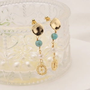 Détail de boucles d'oreilles pendantes plaquées or 18k avec turquoise et perles
